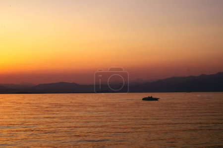 Téléchargez les photos : Une silhouette de bateau dans la mer au coucher du soleil - en image libre de droit