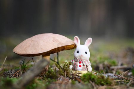 Photo for A cute white bunny statue next to a Russula mushroom in a forest - Royalty Free Image