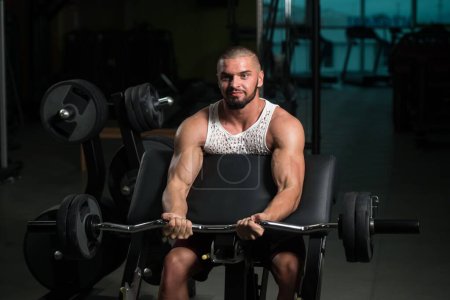 Téléchargez les photos : Un homme musclé faisant l'exercice lourd de poids pour des biceps avec Barbell dans le gymnase - en image libre de droit