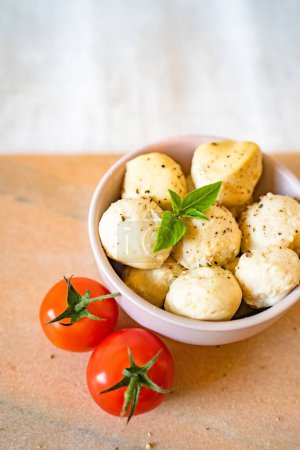 Photo for A vertical closeup of fresh tomatoes and a bowl of mozzarella balls. - Royalty Free Image