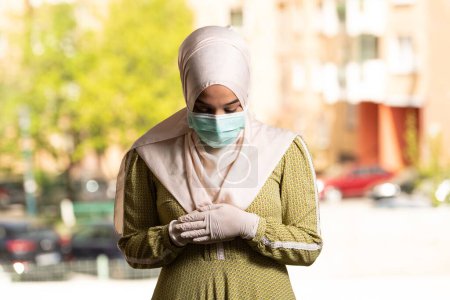 Foto de Una joven musulmana rezando en la mezquita con máscara quirúrgica y guantes - Imagen libre de derechos