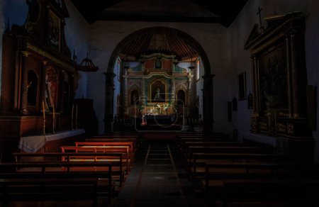 Foto de El interior de la Iglesia de San Pedro en Vilaflor con el altar y bancos en tonos oscuros - Imagen libre de derechos