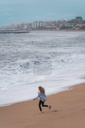 Foto de Un disparo vertical de una mujer corriendo alrededor de una playa de arena en Oporto, Portugal - Imagen libre de derechos