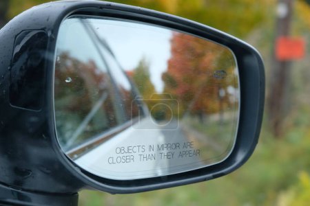 Téléchargez les photos : Un gros plan du miroir latéral de la voiture avec le reflet flou des arbres d'automne - en image libre de droit