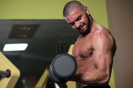 Foto de Un hombre atractivo de buen aspecto caucásico que hace ejercicio Peso con pesas que entrenan en gimnasio - Imagen libre de derechos