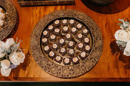 Photo for Tasty Dark Chocolate Cherry cookies and  bouquets on wooden table at a wedding party, top view shot - Royalty Free Image