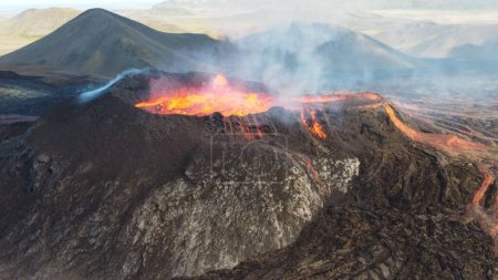 Téléchargez les photos : Un paysage de volcan Mauna Loa en éruption à Hawaï avec de la fumée et un horizon bleu ciel - en image libre de droit