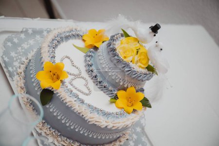 Foto de Una foto de alto ángulo de un sabroso pastel de bodas decorado con palomas y flores amarillas - Imagen libre de derechos