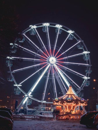 Téléchargez les photos : Un plan vertical du parc d'attractions avec une grande roue éclairée et un carrousel la nuit à Kosice, Slovaquie - en image libre de droit