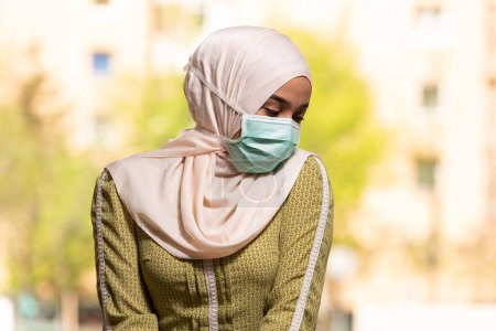 Téléchargez les photos : Une jeune musulmane priant dans une mosquée avec masque chirurgical et gants - en image libre de droit