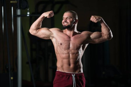 Téléchargez les photos : Portrait d'un modèle de fitness attrayant montrant son corps athlétique après une séance d'entraînement au gymnase - en image libre de droit