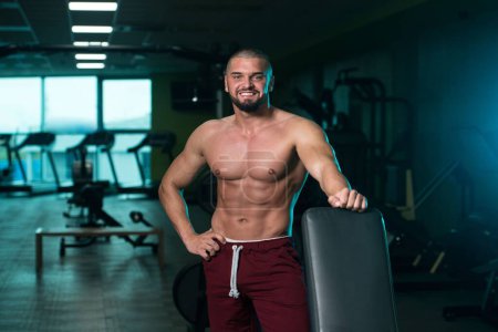 Foto de Un guapo caucásico y atractivo joven masculino con cuerpo muscular relajante en el gimnasio - Imagen libre de derechos