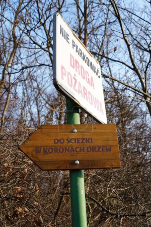Foto de Una señal de advertencia y una tabla de madera que muestra el camino a la Korona Drzew en Poznan, Polonia - Imagen libre de derechos