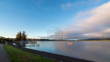 Photo for A boat on the lake surface in New Zealand with an asphalt road near it - Royalty Free Image