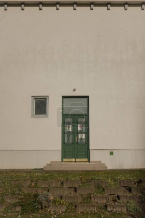 Foto de Un disparo vertical de una puerta cerrada de metal verde instalada en una pared blanca - Imagen libre de derechos