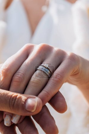 Foto de Un primer plano vertical de un macho sosteniendo la mano de una hembra con un anillo de compromiso en su dedo - Imagen libre de derechos