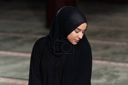 Téléchargez les photos : Une belle musulmane dans une mosquée portant une robe noire avec hijab. Foi musulmane, culture. - en image libre de droit