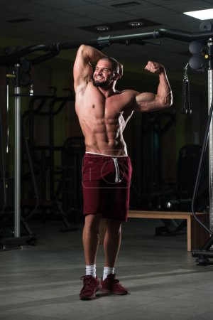 Téléchargez les photos : Portrait vertical d'un modèle de fitness attrayant montrant son corps sportif après une séance d'entraînement - en image libre de droit