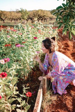 Téléchargez les photos : Une belle femme jouissant de l'odeur des fleurs dans un jardin. - en image libre de droit