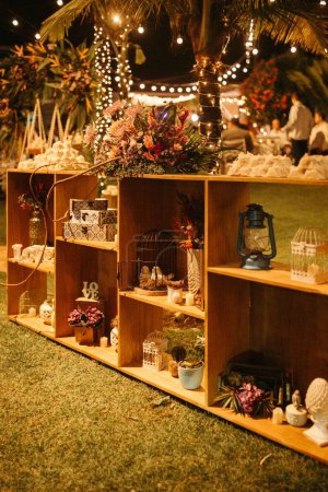 Foto de Flores decoradas y artesanías de criada en estantes de madera en el jardín por la noche - Imagen libre de derechos