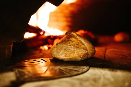 Téléchargez les photos : Le pain croustillant frais cuit au four étant retiré du four chaud avec la peau - en image libre de droit