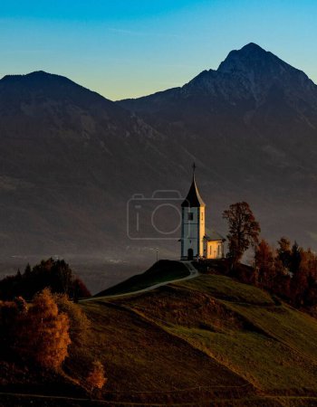 Téléchargez les photos : Un plan vertical de l'église Saint-Primoz et Felicijan sur une colline à feuillage persistant à Jamnik, Slovénie - en image libre de droit