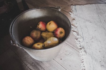 Foto de Un tiro de alto ángulo de un cubo lleno de manzanas orgánicas frescas y peras en una choza de madera polvorienta - Imagen libre de derechos
