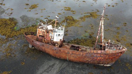 Téléchargez les photos : Un navire abandonné sur la côte verte mousseuse île au bord de la mer - en image libre de droit