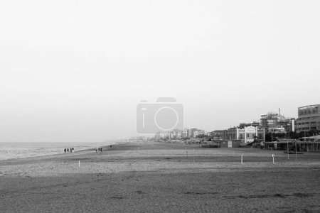 Téléchargez les photos : Une échelle de gris d'un paysage marin avec vue sur la plage et la station balnéaire, ciel en arrière-plan - en image libre de droit