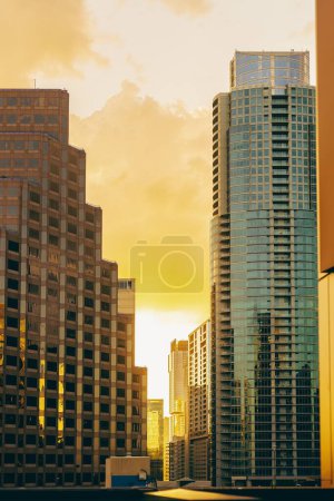 Foto de Una vista aérea vertical de edificios de vidrio modernos contra el fondo amarillo brillante del cielo del atardecer en Austin - Imagen libre de derechos