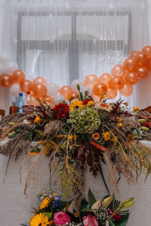 Foto de Un plano vertical de una mesa de eventos decorada con un arreglo floral y globos en el fondo - Imagen libre de derechos