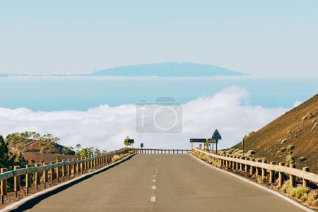 Téléchargez les photos : Un beau cliché d'une autoroute entre des collines avec un fond de mer et des nuages à Tenerife - en image libre de droit