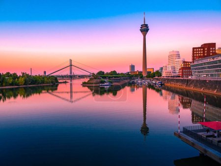 Die Skyline des Düsseldorfer Hafens spiegelt sich in der Abenddämmerung im Wasser