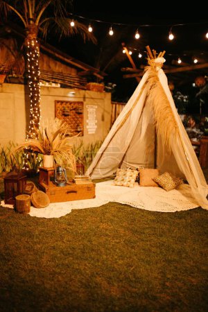 Téléchargez les photos : Une tente tipi installée dans un jardin avec des décorations en bois - en image libre de droit