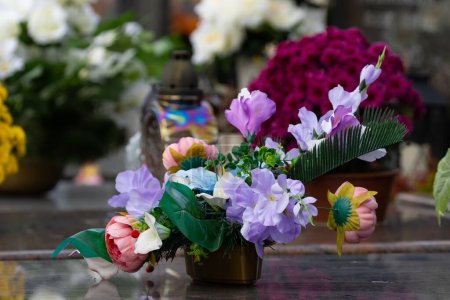 Téléchargez les photos : Plan rapproché de fleurs sur des pierres tombales dans un cimetière - en image libre de droit