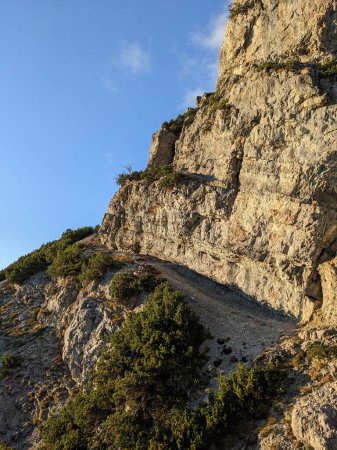 Foto de Una hermosa vista vertical de un lado rocoso de una montaña con cielo azul - Imagen libre de derechos