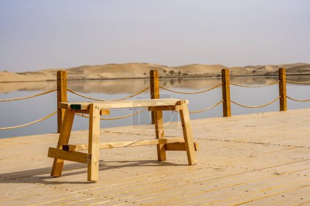Foto de Un banco de madera vacío en el muelle contra el fondo del lago. - Imagen libre de derechos