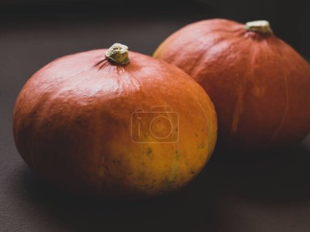 Photo for A selective focus shot of a hokkaido pumpkin on the table with blur dark background - Royalty Free Image