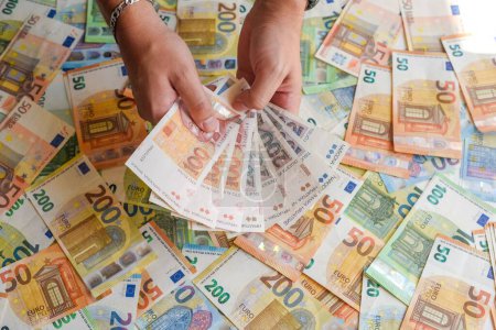 Téléchargez les photos : Une main humaine tenant les billets en kuna croate sur fond de billets en euros - en image libre de droit