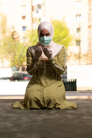 Téléchargez les photos : Jeune femme musulmane priant dans la mosquée avec masque chirurgical et gants - en image libre de droit