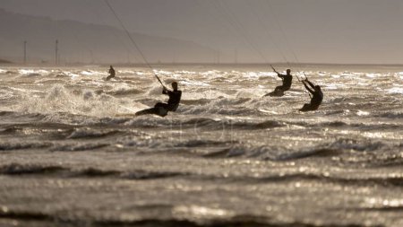 Téléchargez les photos : Les silhouettes des kiteboarders ont traversé l'eau. New Brighton, Merseyside, Angleterre. - en image libre de droit