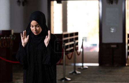 Photo for A beautiful Muslim woman in a black dress with hijab praying in a mosque. - Royalty Free Image