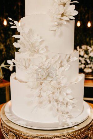 Foto de Un plano vertical de un pastel de boda minimalista blanco de cinco niveles sobre una mesa en un restaurante - Imagen libre de derechos