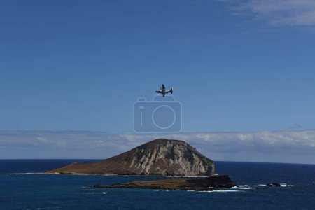 Foto de Un avión volando sobre islas rocosas y costa en un día soleado - Imagen libre de derechos