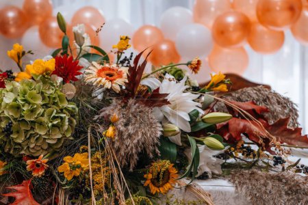 Photo for An event table decorated with a floral arrangement and balloons in the background - Royalty Free Image