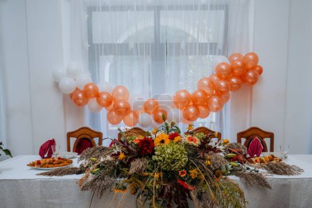 Foto de Una mesa de eventos decorada con un arreglo floral y globos en el fondo - Imagen libre de derechos