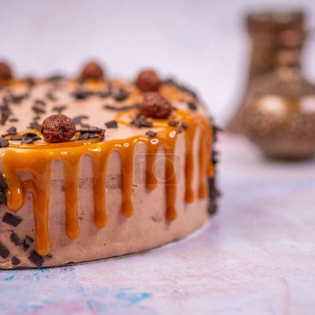 Photo for A closeup of the cake with caramel cream decorated with chocolate shavings and chocolate balls on a blurry background - Royalty Free Image