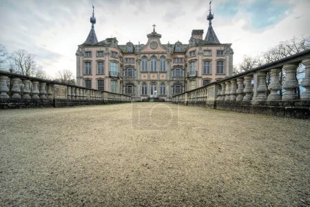 Téléchargez les photos : Vue en angle bas de l'approche du château de Poeke, près de Poeke, dans la province belge de Flandre orientale, entouré d'arbres par une journée nuageuse - en image libre de droit