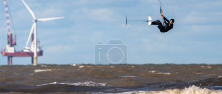 Photo for A kiteboarder hovering above the water's surface. New Brighton, Merseyside, England. - Royalty Free Image