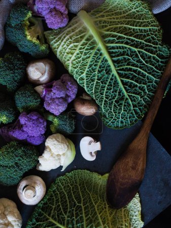 Téléchargez les photos : Une vue verticale de dessus de nombreux types de légumes verts avec une cuillère en bois à côté d'eux - en image libre de droit